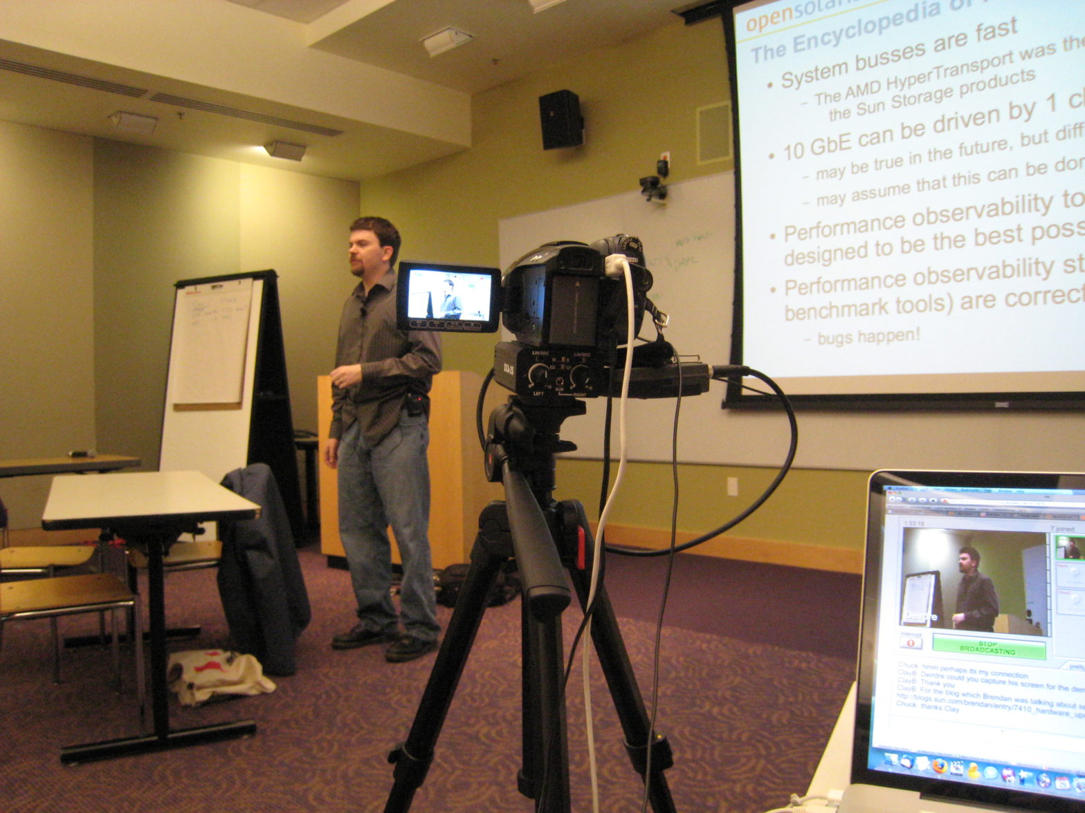 Brendan speaking in front of a projector screen, videocamera in the foreground