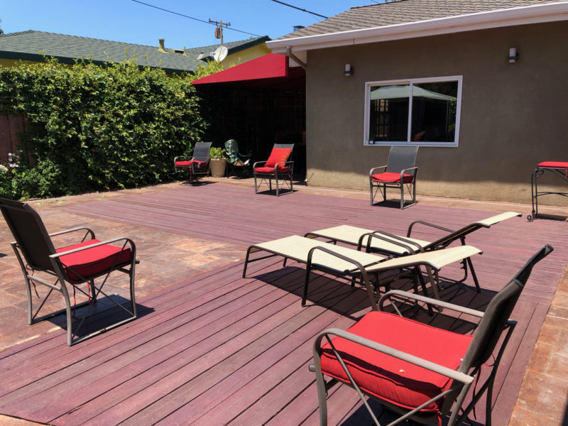 Back yard with wooden deck and chairs.