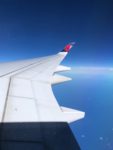 view over an airplane wing with the Delta logo on the wingtip, over the Pacific Ocean