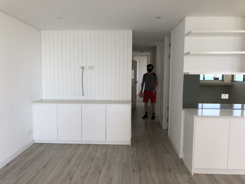 Brendan seen down a hallway, white cabinets and kitchen area in the foreground