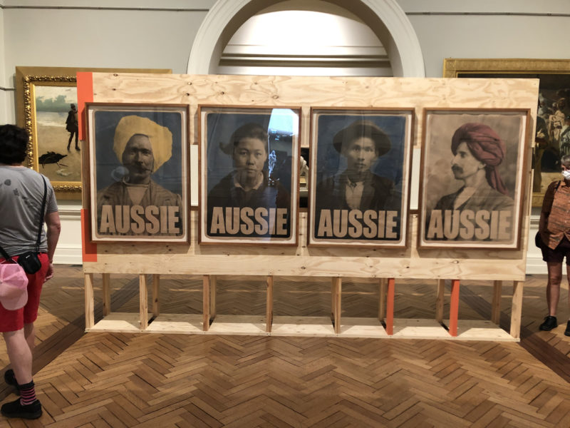 artwork: four posters showing antique photographs of people Chinese and Indian descent, each labeled "Aussie"