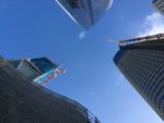looking up between three tall buildings, two of them under construction