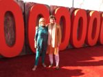 Deirdré and Brendan in front of giant red zeros (part of the 100,00,000 sign)