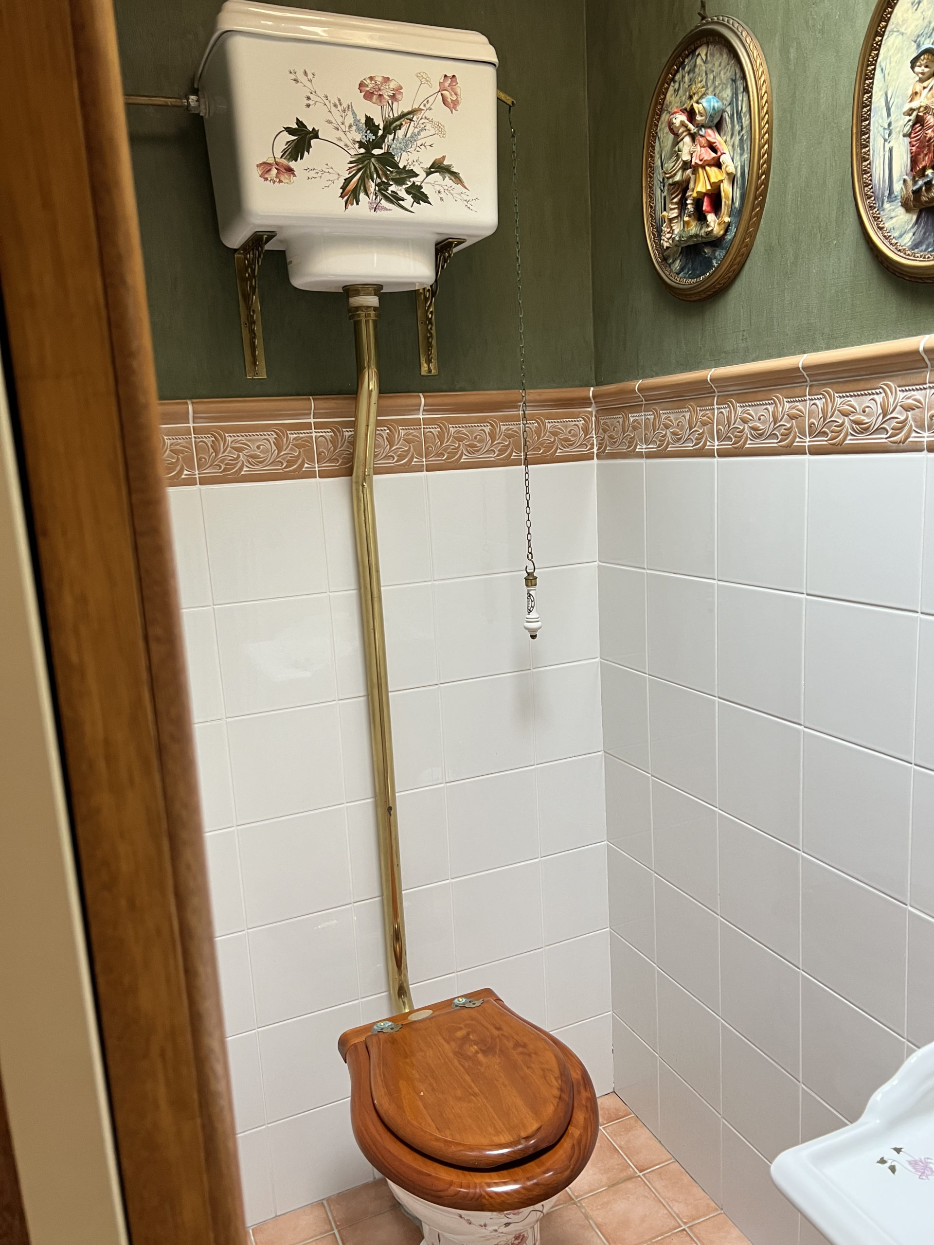 old fashioned high-tank toilet with chain, decorated ceramic