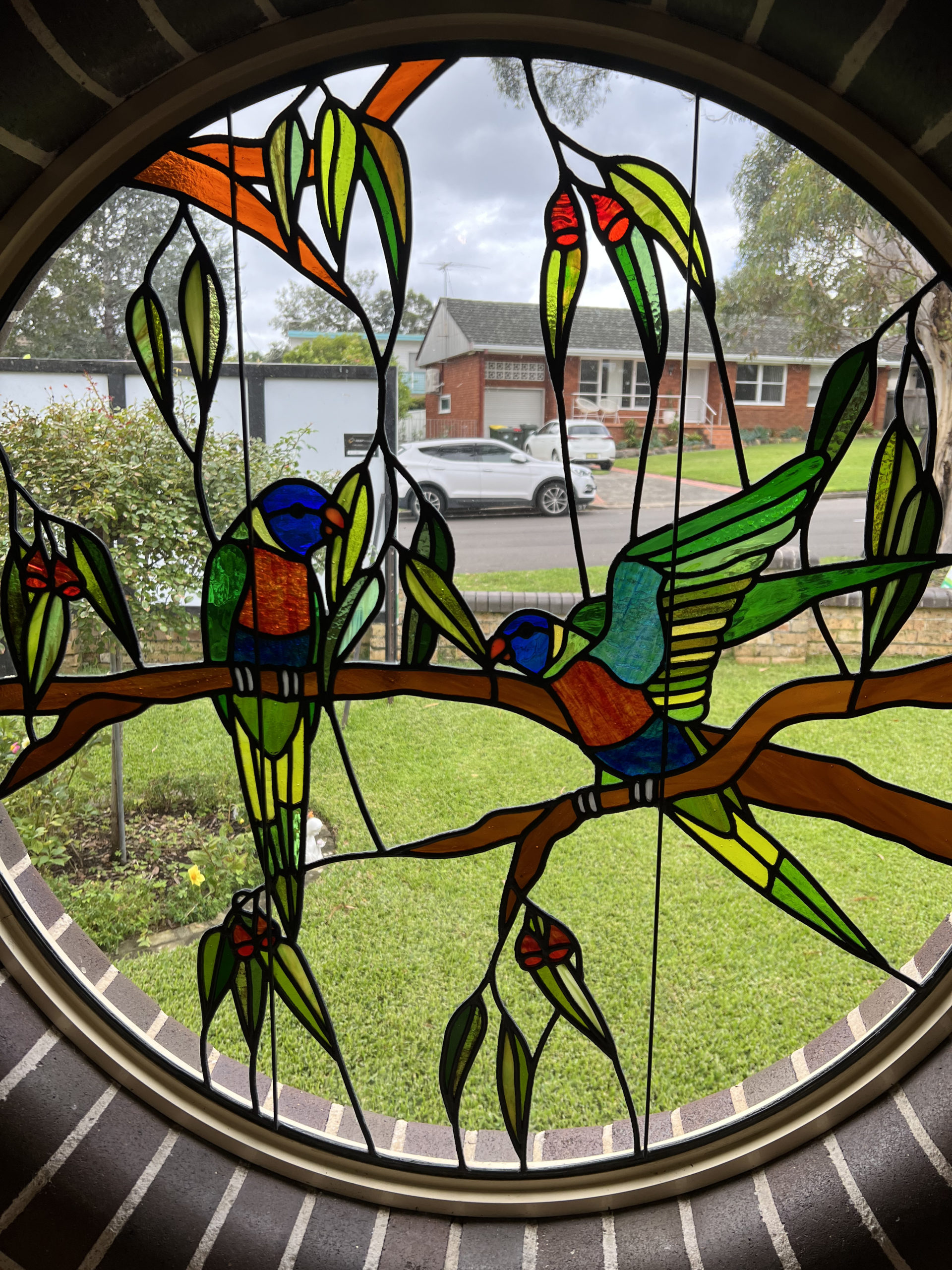 round stained glass window with two rainbow lorikeets