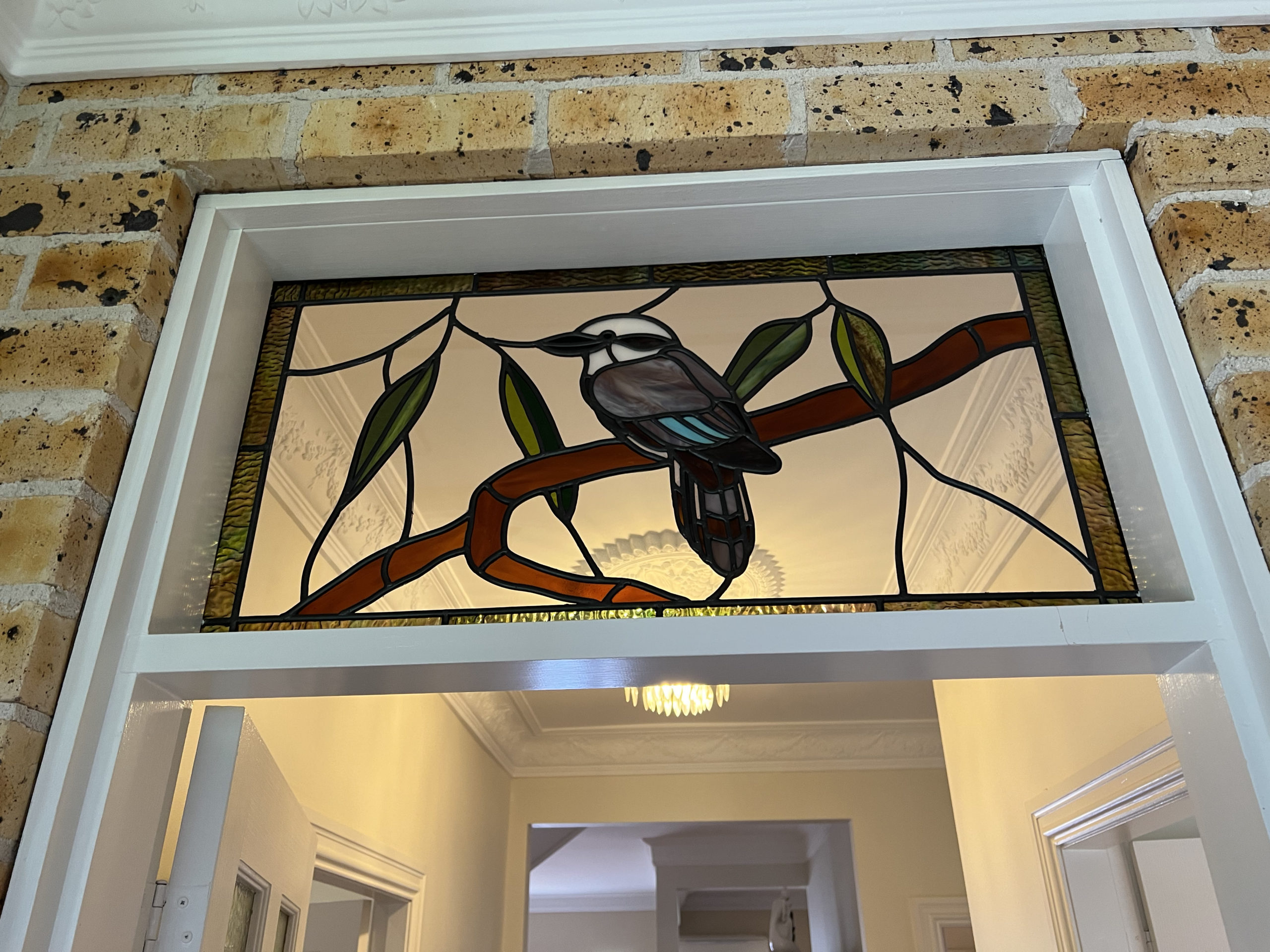 stained glass window above a door, showing a kookaburra on a branch