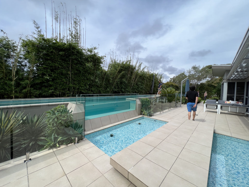 a pool with an overflow waterfall leading to a reflecting pond