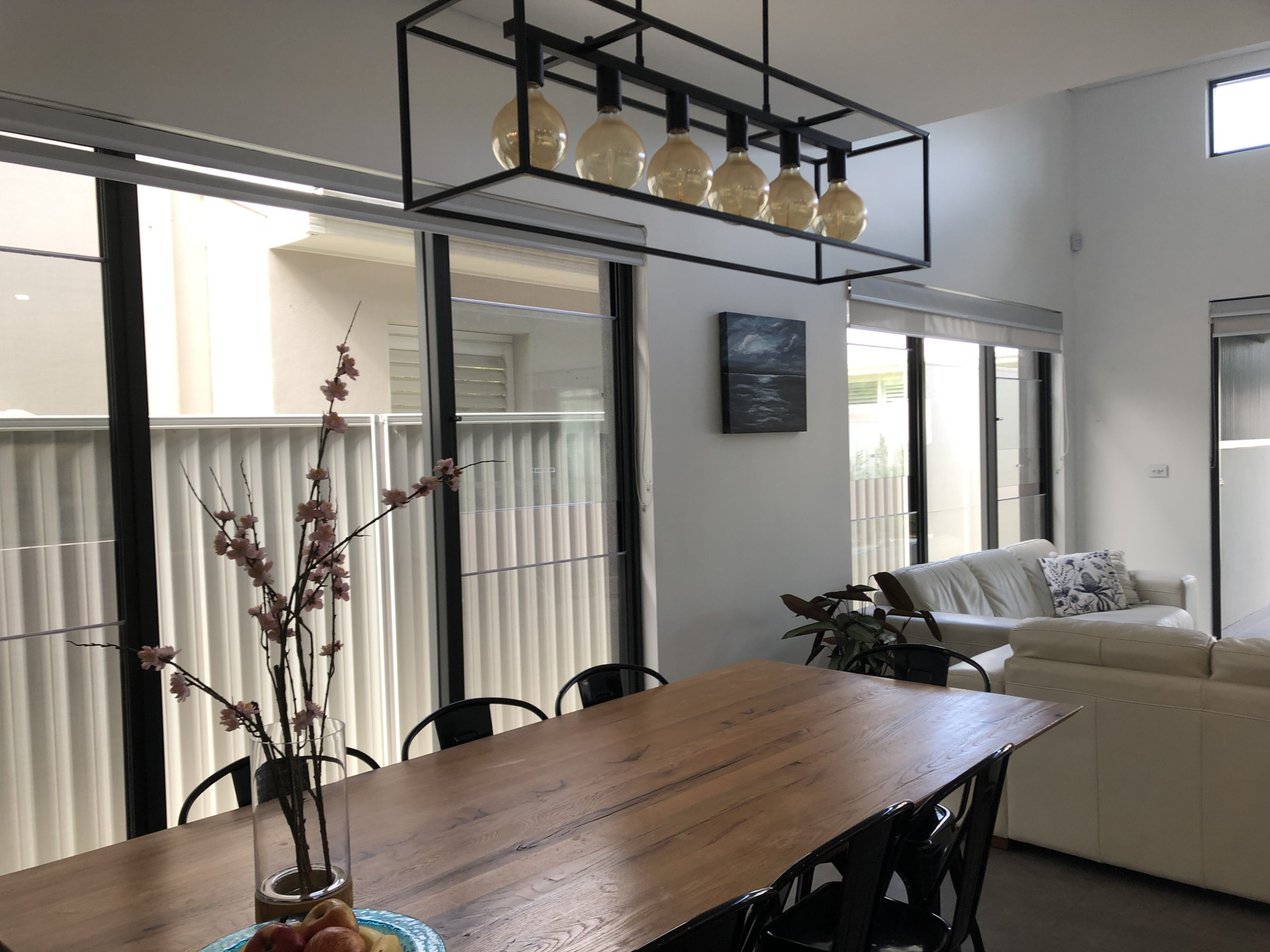 nicely designed room with a huge window looking onto a fence and the neighboring house