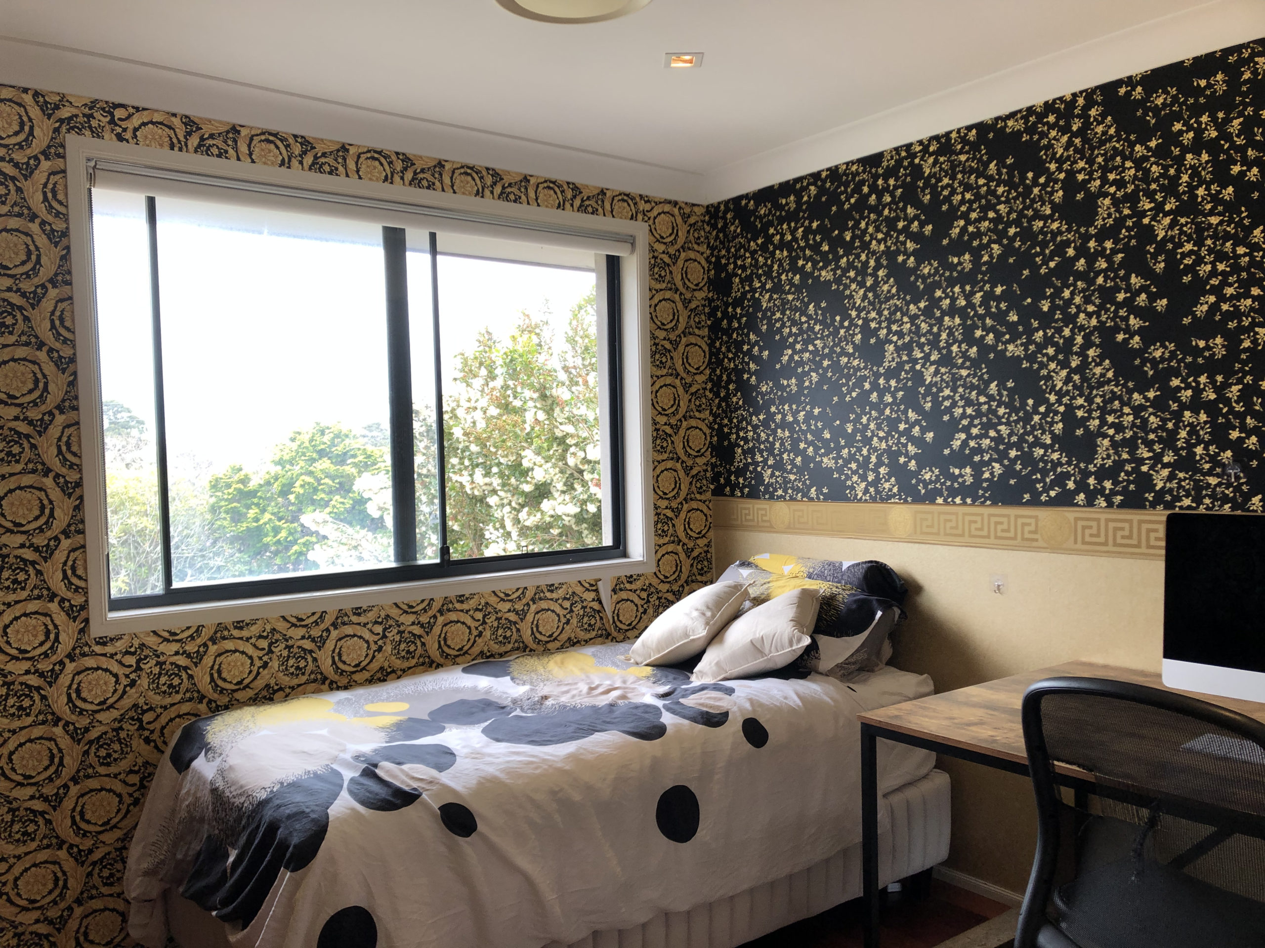 view of a bedroom with complicated dark blue and gold wallpaper