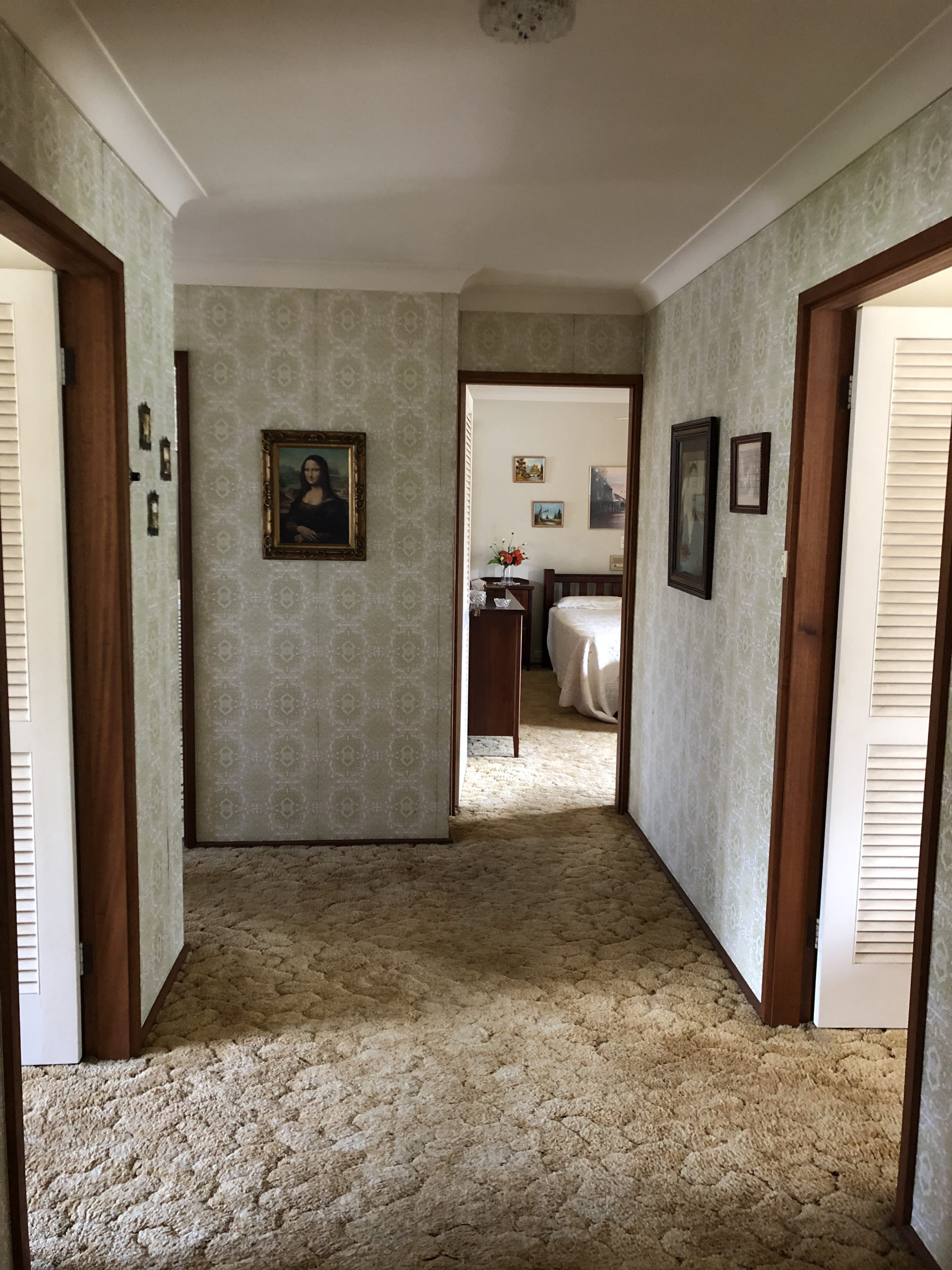 hallway with beige textured carpet and a print of the Mona Lisa