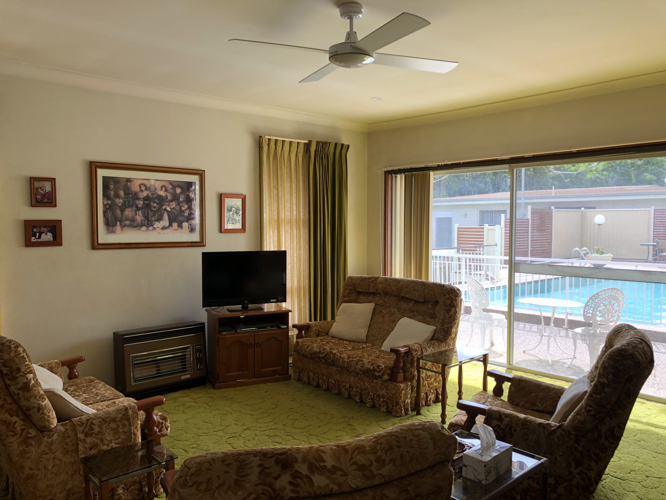 living room with 1970s furniture, textured avocado colored carpet, and a view of the pool