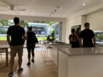 random people viewing a house, more visible in the backyard beyond