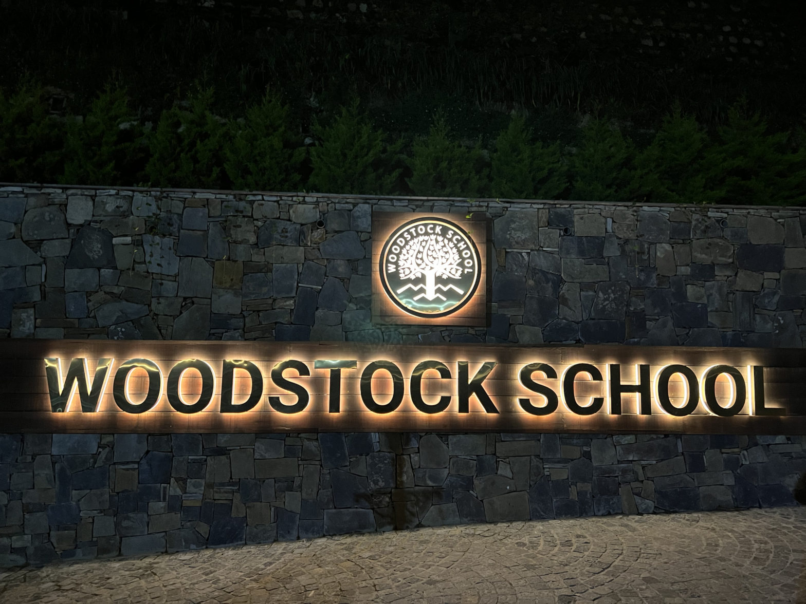 Woodstock School entry sign, illuminated at night
