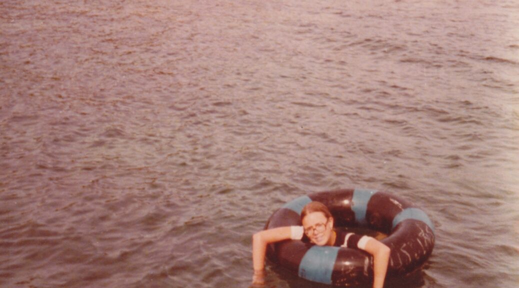my in an inflated tire inner-tube, floating with my arms hanging over the side in an otherwise empty expanse of water. I look quizzical and tired