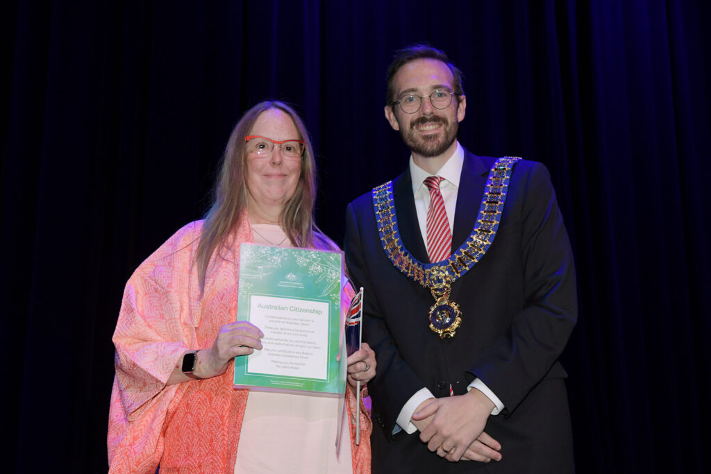 myself with Mayor Jack Boyd on stage, me holding the cover sheet of my citizenship certificate